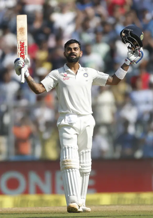 Virat Kohli raises his bat and helmet