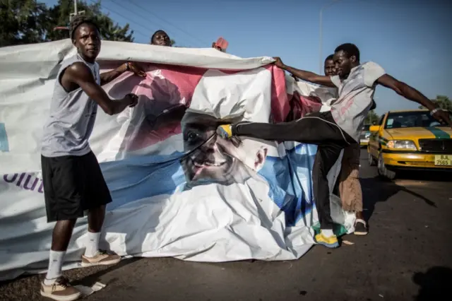 Supporters of the newly elected Gambia"s President Adama Barrow kick a poster of the incumbent Yahya Jammeh in Serekunda on December 2, 2016