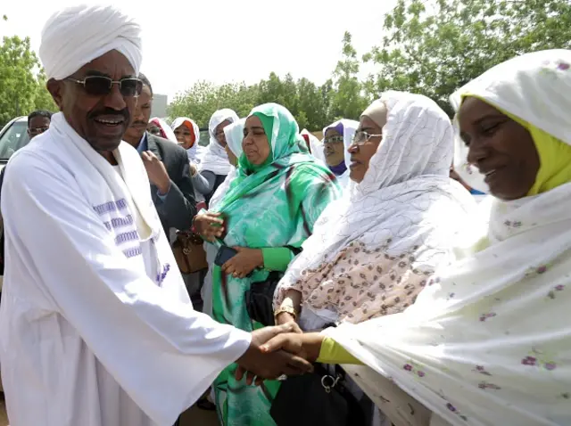 Sudanese President Omar al-Bashir (L) and candidate in the presidential elections greets supporters as he arrives at a polling station to cast his vote at the Saint Francis school in Khartoum on April 13, 2015.
