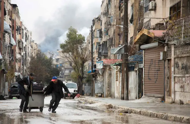 Smoke is seen billowing in the background on December 14, 2016 in this picture taken in a rebel-held neighbourhood in the northern city of Aleppo.