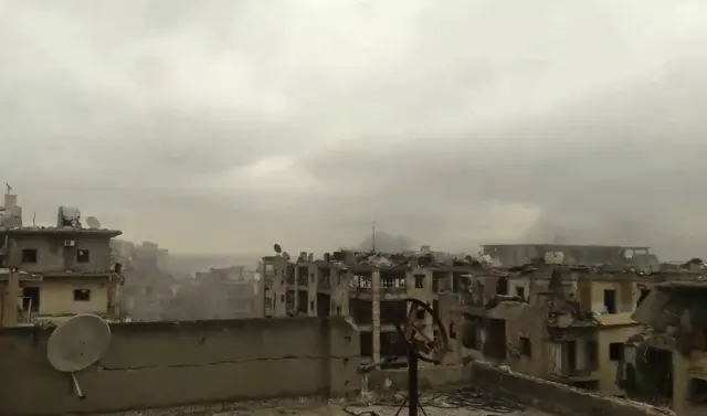 In this still image taken from video released by a Syrian activist Wednesday smoke rises in the distance alongside the sound of heavy bombardment in east Aleppo