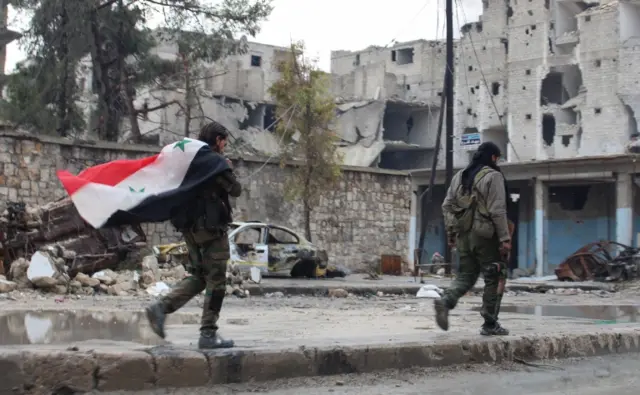 Syrian soldiers are seen walking on one of the eastern neighbourhoods streets in the northern city of Aleppo, Syria, on 14 December