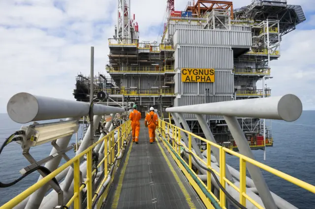 Two gas workers walking along the gas platform, at sea