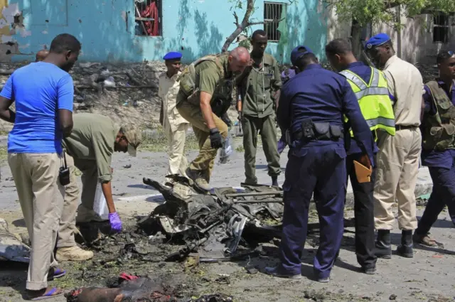 Somali soldiers stand over the wreckage of a car bomb