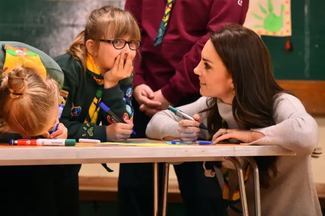 The Duchess of Cambridge, kneeling by a table with two young Cubs, taking part in drawing