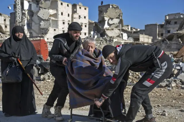 An elderly Syrian man is carried during an evacuation operation of rebel fighters and their families from rebel-held neighbourhoods of Aleppo.