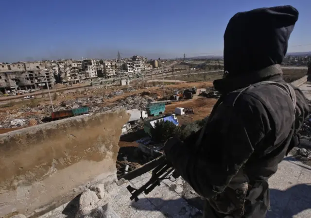 A member of the pro-government forces watches buses in the distance during the evacuation operation of rebel fighters and their families from rebel-held neighbourhoods in Aleppo