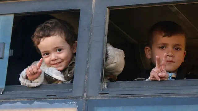 Syrian children, who were evacuated from rebel-held neighbourhoods in the embattled city of Aleppo, gesture as they arrive in the opposition-controlled Khan al-Aassal region