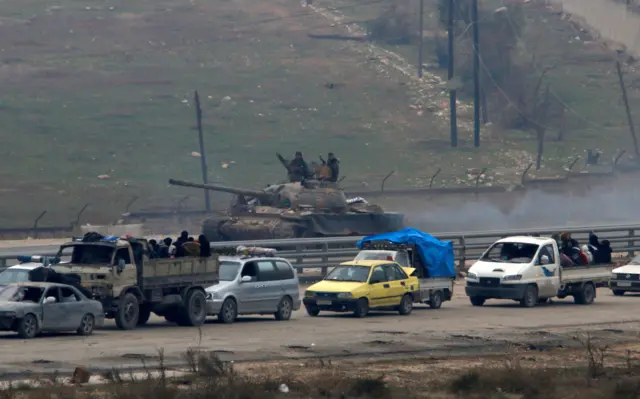 Forces loyal to Syria"s President Bashar al-Assad watch from a tank as an evacuation convoy turns back.