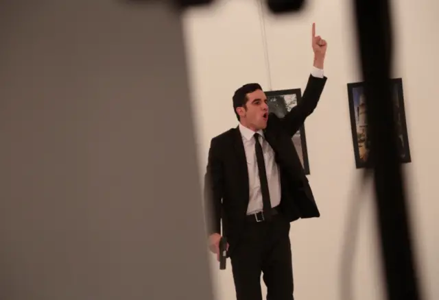 gunman gestures after shooting the Russian Ambassador to Turkey, Andrei Karlov, at a photo gallery in Ankara, Turkey