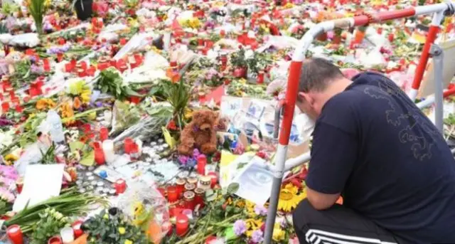 A man bows his head near a memorial for nine people shot dead in Munich