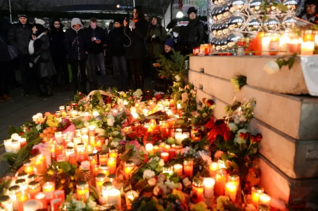 People place flowers and candles in tribute to the victims at the site of the lorry attack in Berlin