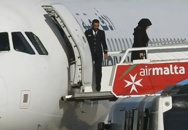 People disembark from a hijacked Libyan Afriqiyah Airways Airbus A320 on the runway at Malta Airport, December 23,