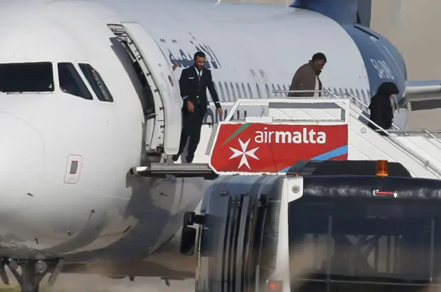 People disembark from a hijacked Libyan Afriqiyah Airways Airbus A320 on the runway at Malta Airport, December 23,