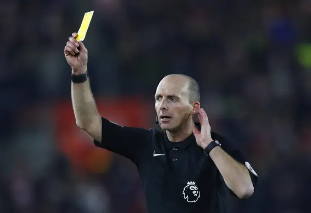 Mike Dean shows a yellow card