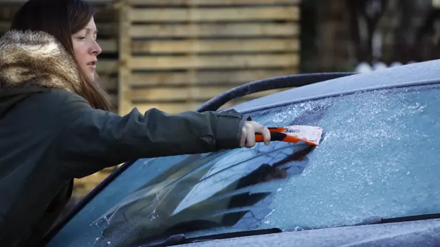 Woman scraping ice off car