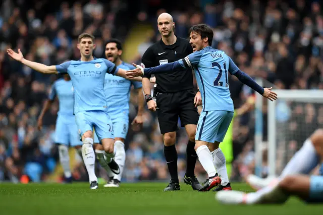 Anthony Taylor surrounded by City players