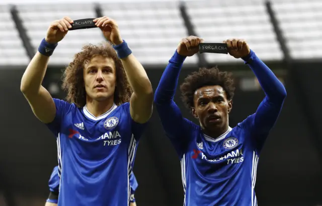 Luiz and Willian hold black armbands aloft