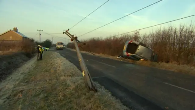 Broken power pylon with crashed car