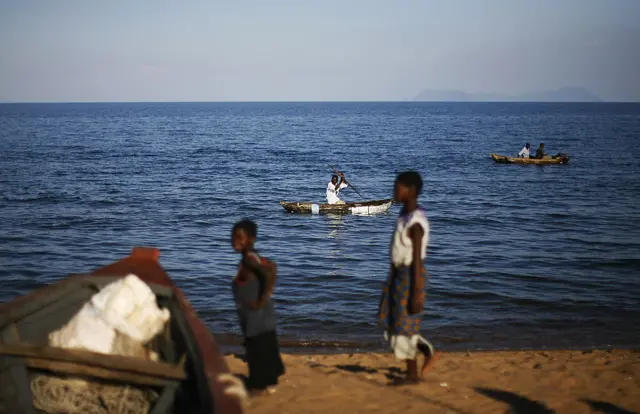 fishermen paddle on canoes on the shore of Lake Malawi