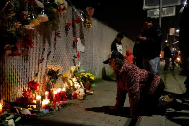People pay respects outside the scene of the Oakland warehouse fire