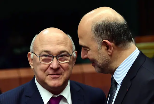 French Finance Minister Michel Sapin (L) and European Commissioner for Economic and Financial Affairs, Taxation and Customs Pierre Moscovici speak together ahead of a Eurogroup finance ministers meeting at the European Council in Brussels, on December 5, 2016.