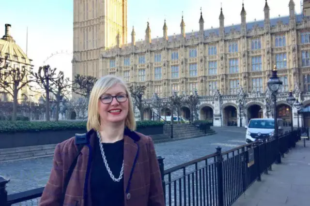 Emma Alfieri standing in the foreground of the Houses of Parliament