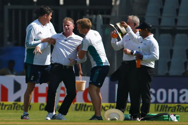 Umpire Paul Reiffel is helped by the support staff