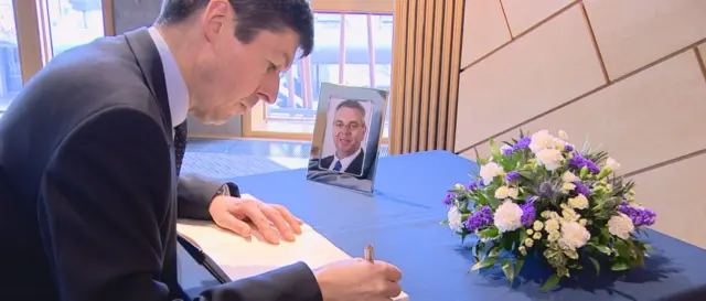 Presiding Officer Ken Macintosh signs the condolence book for the late Alex Johnstone.