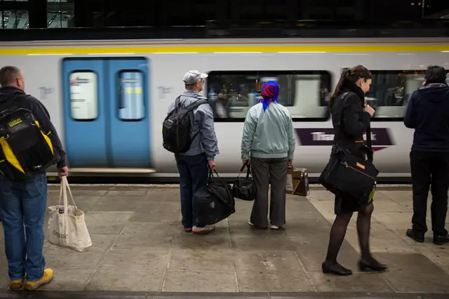 Commuters wait on platform as train arrives at station