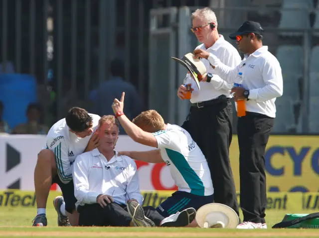 Umpire Paul Reiffe is looked over by the medical team