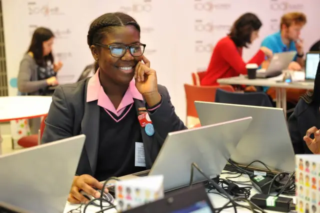 Girl in uniform, at computer, smiling