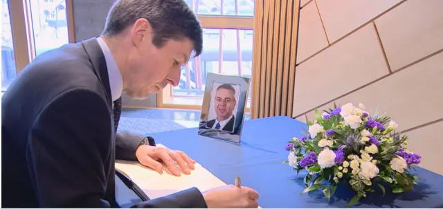 Presiding Officer Ken Macintosh signs the condolence book for Alex Johnstone