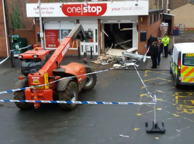 Digger in road with hole in the wall