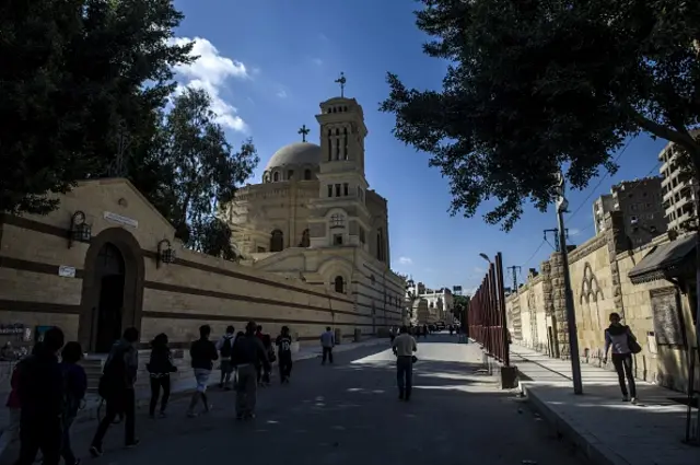 Tourists walk outside the Hanging Church in the Coptic Christian neighbourhood of old Cairo on April 10, 2015