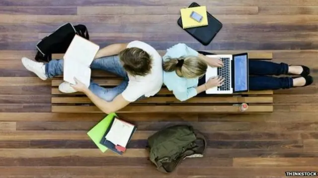 Two students sitting back to back studying