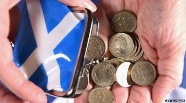 Person tipping a purse with a Saltire on it and holding pound coins