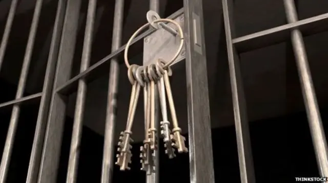 Prison cell with keys hanging from unlocked cell door