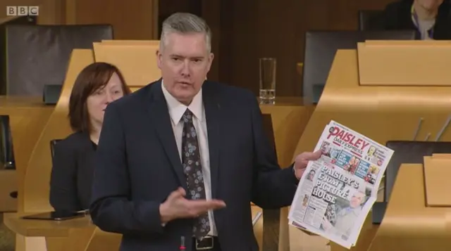 George Adam holds a copy of the Paisley Daily Express