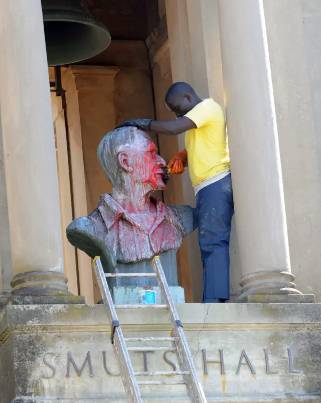 A worker cleans off paint left by protesting students the day after violent pretests at the University of Cape Town where paintings from the walls of the main halls where burned along with vehicles, in Cape Town, South Africa, 17 February 2016