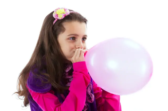 Girl blowing up a balloon