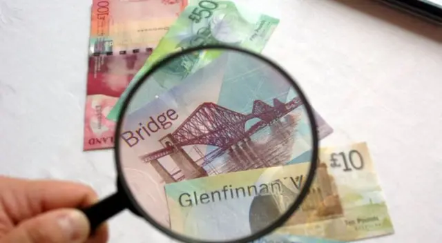 Magnifying glass hovering over Scottish bank notes