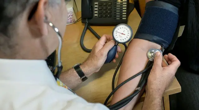 GP checking patient's blood pressure