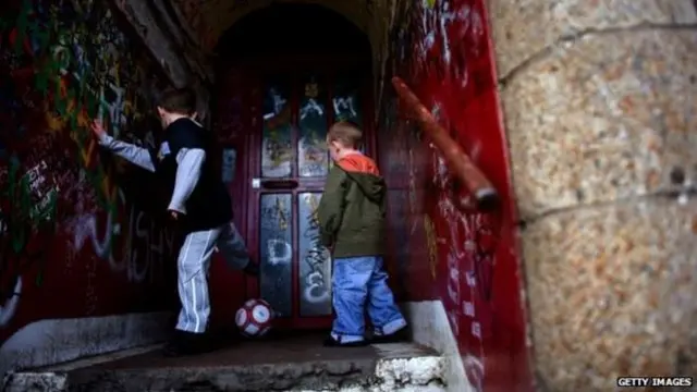 Children play in a close covered in graffiti