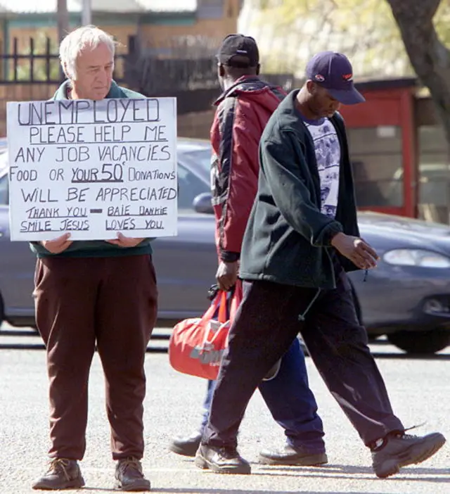 A white South African begs for money, 02 August 2000, while two blacks are passing through, on a street in Johannesburg