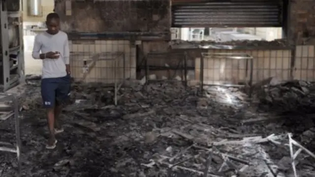 A student walks through the remains of the Science Center at the University of the North-West University in Mafikeng, South Afric