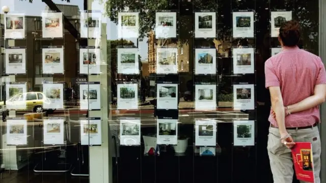 A man looks in an estate agents window