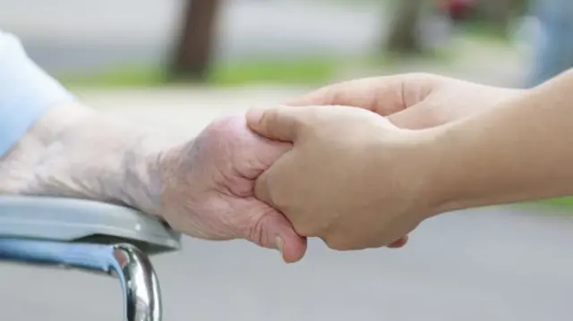 Nurse holding an elderly woman's hand