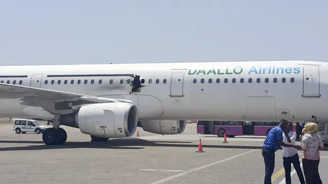 In this photo taken Tuesday, Feb. 2, 2016, a hole is seen in a plane operated by Daallo Airlines as it sits on the runway of the airport in Mogadishu, Somali