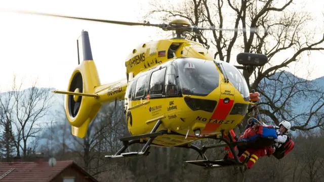 A paramedic stands on the ski of a rescue helicopter near the site of a train accident near Bad Aibling, Germany, on 9 February 2016